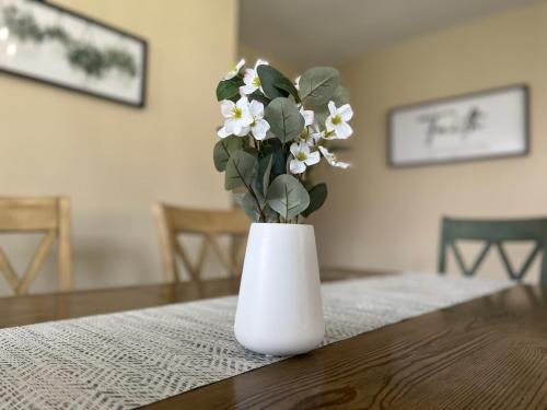 a white vase with white flowers sitting on a table at Host Hubble Private Rooms in Southern Lakeland in Lakeland