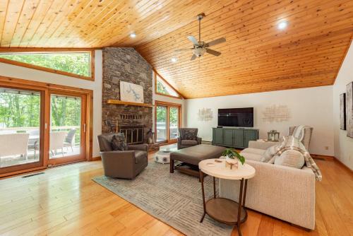 a living room with a vaulted ceiling and a stone fireplace at Cottage On The Cove by Railey Vacations in Swanton