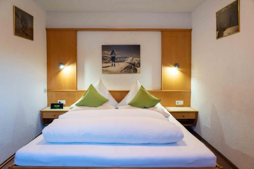 a bedroom with a large white bed with green pillows at Haus Ladner in See