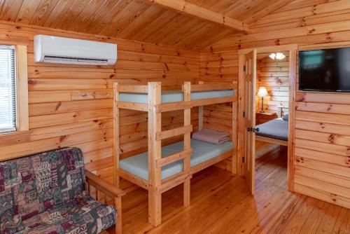 a log cabin with a bunk bed and a tv at Sun Outdoors Association Island in Henderson Harbor