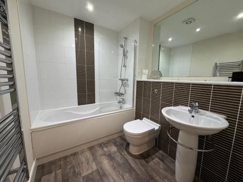 a bathroom with a sink and a tub and a toilet at Three bed apartment in the Tower in Swansea