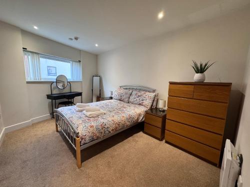 a bedroom with a bed and a dresser with a mirror at Three bed apartment in the Tower in Swansea