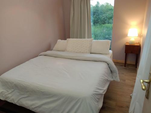 a bed with white sheets and pillows in a room with a window at Lux tree house karen in Nairobi