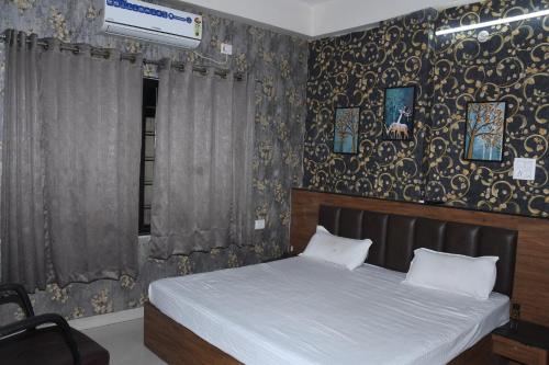 a bedroom with a bed and a wall with wallpaper at Manas homes in Gwalior