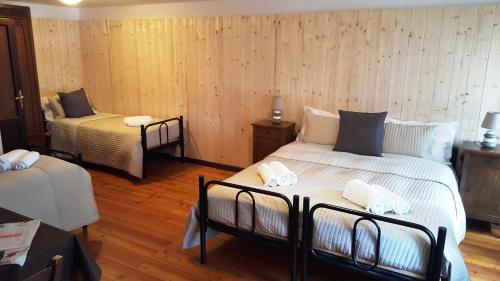 two beds in a room with wooden walls and wooden floors at Locanda Aquila Bianca in Valprato Soana