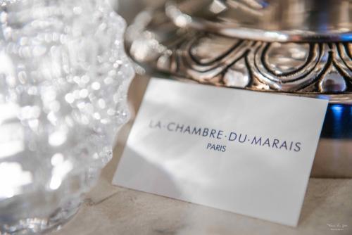 a white card sitting on a table next to a glass at La Chambre du Marais in Paris