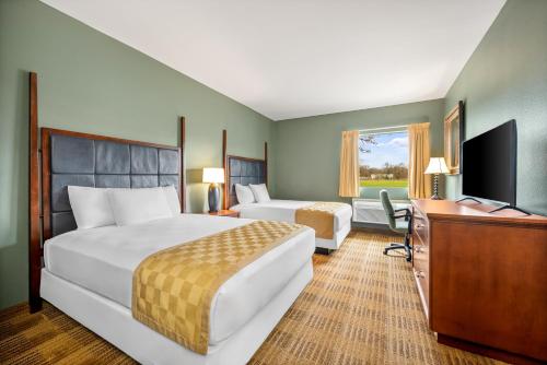 a hotel room with two beds and a desk and a television at Americas Best Value Inn Somerville Texas in Somerville