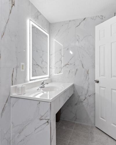a white bathroom with a sink and a mirror at Western Inn by Capital O Cleburne TX in Cleburne