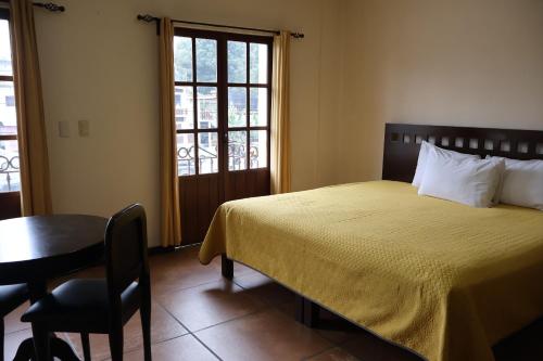 a bedroom with a bed and a table and a window at Hotel El Cafetalero in Xicotepec de Juárez