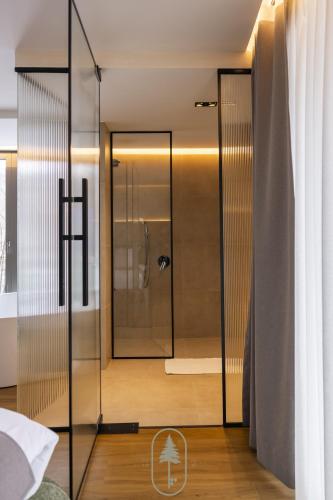 une salle de bain avec douche et porte en verre dans l'établissement Pine Hotel & Spa Brezovice, à Brezovicë