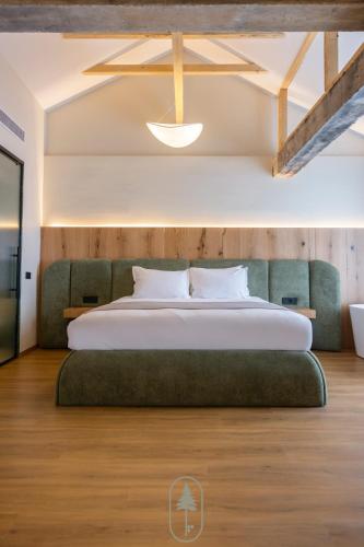 une chambre avec un grand lit avec un canapé vert dans l'établissement Pine Hotel & Spa Brezovice, à Brezovicë