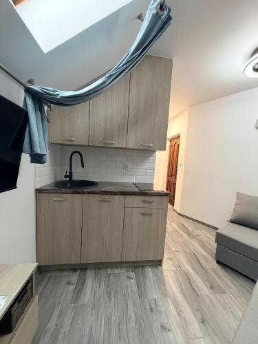 a kitchen with wooden cabinets and a sink in a room at Apartament Hexagon nr 36 in Grzybowo