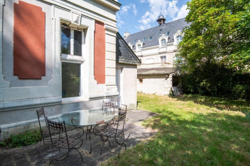 a patio with a glass table and chairs next to a building at Echappée royale in Saint-Benoît-la-Forêt