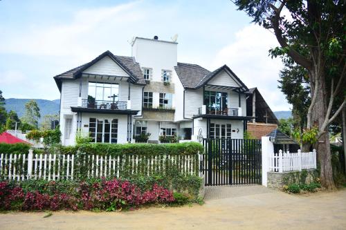 a white house with a white fence and flowers at Unique Cottages in Nuwara Eliya