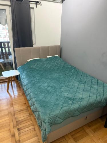 a bed in a room with a green comforter at Stan na dan Despotovac in Despotovac