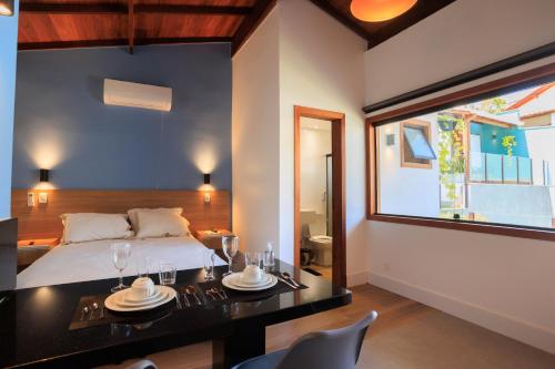 a bedroom with a bed and a table and chairs at Pousada Vinháticos in Nova Lima