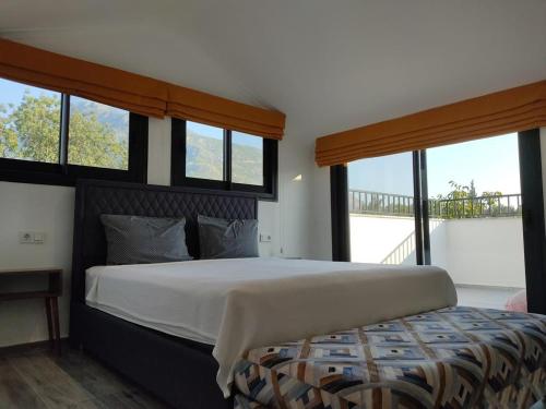 a bedroom with a large bed with windows at Villa Olivin in Fethiye