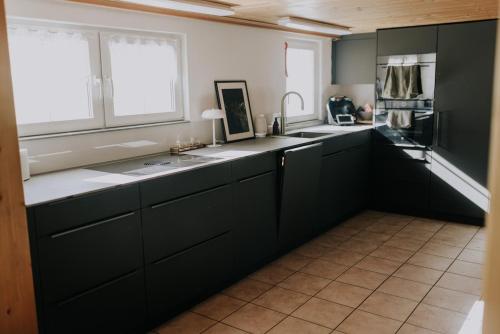 a kitchen with black cabinets and a large window at 4 bedroom house for 8 guests in Brülisau