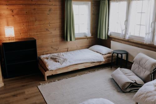 a bedroom with a bed and a couch and windows at 4 bedroom house for 8 guests in Brülisau