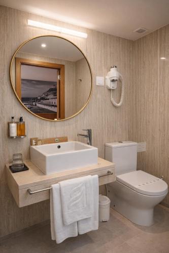 a bathroom with a sink and a toilet and a mirror at Hotel Zenite in Angra do Heroísmo