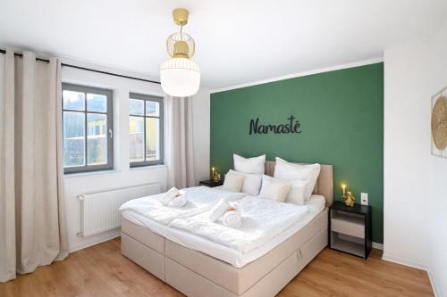 a bedroom with a large white bed with a green wall at NAMASTÉ Homes - Ferienwohnungen - Altstadt - 2 Schlafzimmer in Bad Windsheim