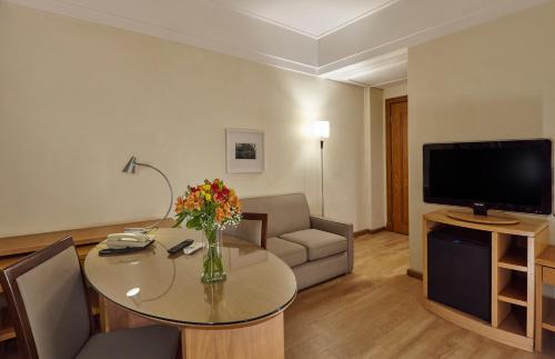 a living room with a table and a television at Hotel Cassino Tower Campinas Cambuí By Nacional Inn in Campinas