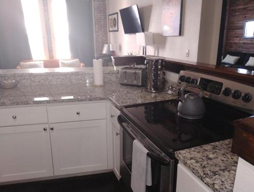 a kitchen with white cabinets and a stove top oven at The Downtown Grizz Loft in Memphis