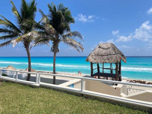 a gazebo on the beach with palm trees and the ocean at Comoda Suite Cancun - BEACH CONDO - 6PX in Cancún