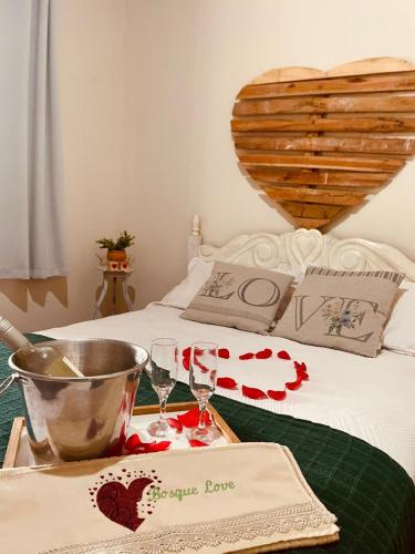 a table with two wine glasses on a bed at Bosque Love in Juatuba