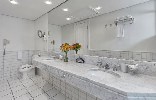 a white bathroom with a sink and a toilet at Hotel Cassino Tower Campinas Cambuí By Nacional Inn in Campinas