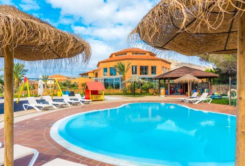 uma piscina com cadeiras e guarda-sóis num resort em Pestana Porto Santo Beach Resort & SPA em Porto Santo