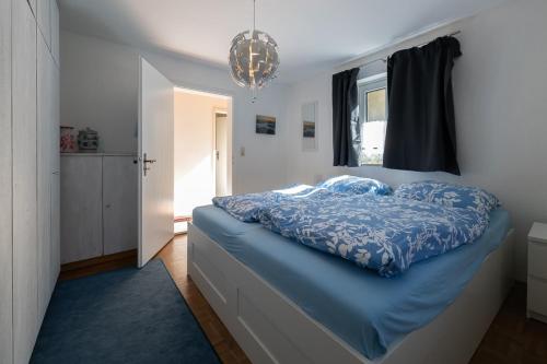 a bedroom with a bed with a blue comforter at Alpenwohnung "Zum Schorschi" mit Bergblick I voll ausgestattet I ruhige Lage in Oberammergau