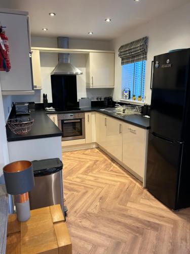 a kitchen with a black refrigerator and a wooden floor at Hotdog House Filey Detached Pet Friendly Eco-House in Hunmanby