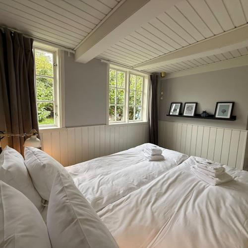 a large white bed in a room with windows at Pensionat Næsgaarden in Allinge