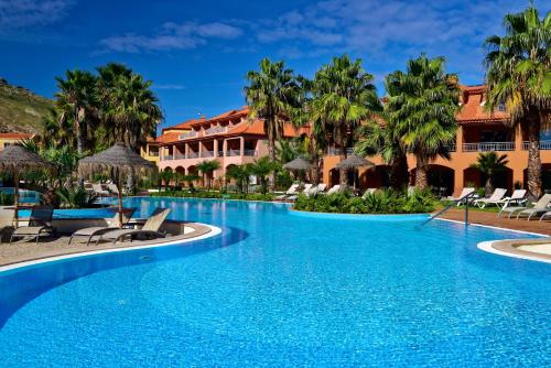 ポルト・サントにあるPestana Porto Santo Premium All Inclusive Beach & SPA Resortのヤシの木が茂るリゾートのスイミングプール