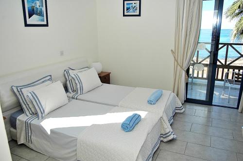 a bedroom with two beds and a balcony at Kymmates Beach Front Villas in Paphos City