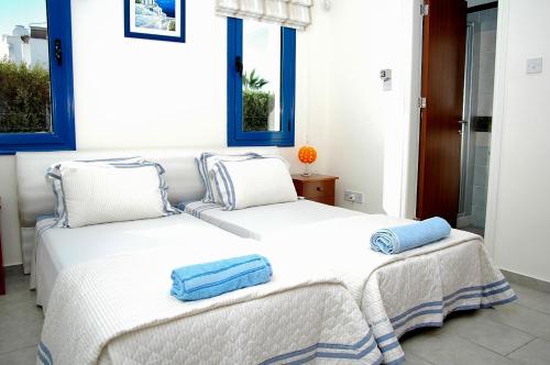 two beds in a room with blue windows at Kymmates Beach Front Villas in Paphos City