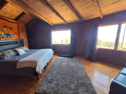 a bedroom with a bed and two windows and a rug at Casacerrolacruz in Pichilemu