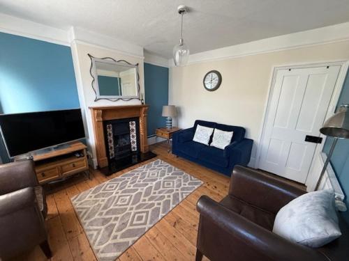 a living room with a tv and a blue couch and a couch at Augustines Cottage, Canterbury centre Free Parking in Canterbury
