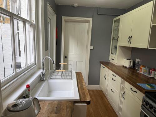 a kitchen with a white sink and a window at Augustines Cottage, Canterbury centre Free Parking in Canterbury