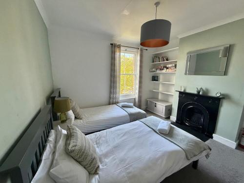 a bedroom with two beds and a fireplace and a tv at Augustines Cottage, Canterbury centre Free Parking in Canterbury