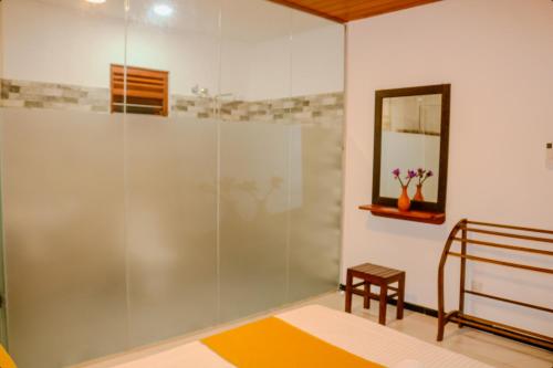 a glass shower in a bedroom with a mirror at Nature Forest Villa in Hikkaduwa