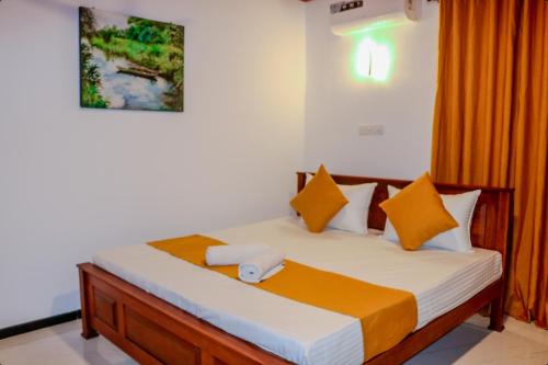a bedroom with a bed with orange and white pillows at Nature Forest Villa in Hikkaduwa
