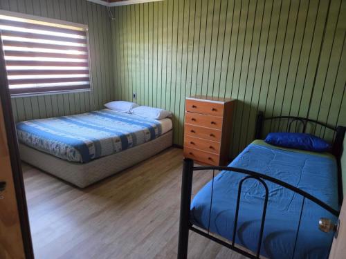 a bedroom with two beds and a dresser in it at Cabañas de Turismo Berolav7 in Puerto Montt