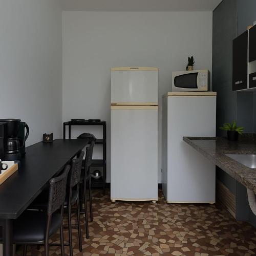 a kitchen with two refrigerators and a table and a microwave at Praia dos Sonhos - Suítes in Itanhaém
