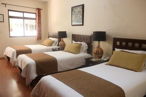 two beds in a room with two lamps at Hotel Plaza San Carlos in Xicotepec de Juárez