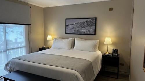 a bedroom with a bed with white sheets and a window at Hotel Nevados de Chillan in Nevados de Chillan