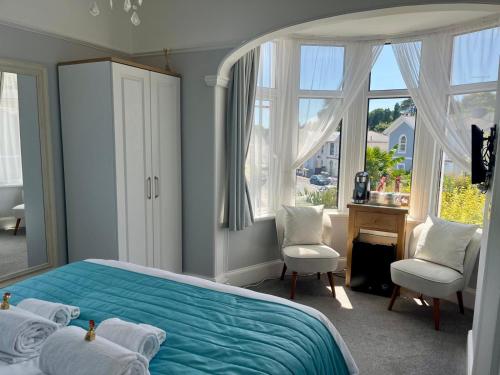 a bedroom with a blue bed and a desk and windows at Bentley Lodge in Torquay
