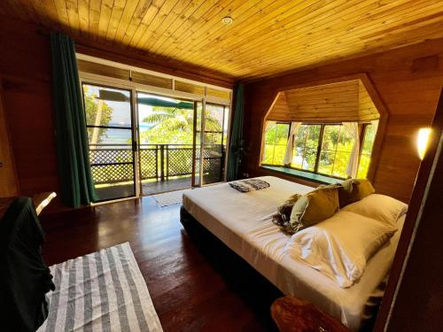 a bedroom with a large bed with a large window at Fare Hotu Villa plus voiture-car in Fitii