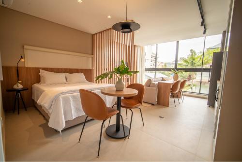 a bedroom with a bed and a table and chairs at Jurerê Sol&Mar Temporada in Florianópolis